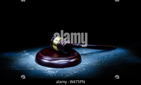 Judge's gavel lies on a stone table. Picture taken with a light brush - Image Stock Photo