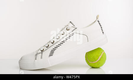 Fashionable white walking shoes with tennis ball on a white background. - image Stock Photo