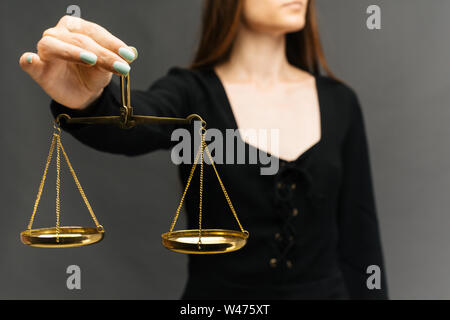 Serious woman holding the justice scale on dark background - image Stock Photo