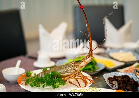 Lobster with parsley on a round white plate near other dishes in the background Stock Photo