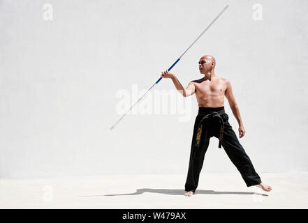 Martial Arts Man exercising with a metal stick staff. Stock Photo