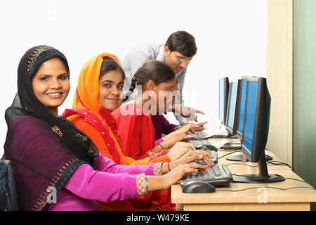 Indian women using computers with teacher assistance Stock Photo