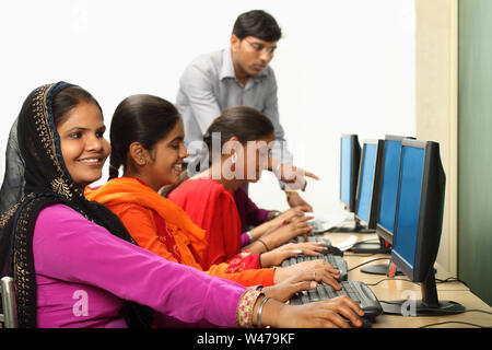 Women using computers with teacher assistance Stock Photo