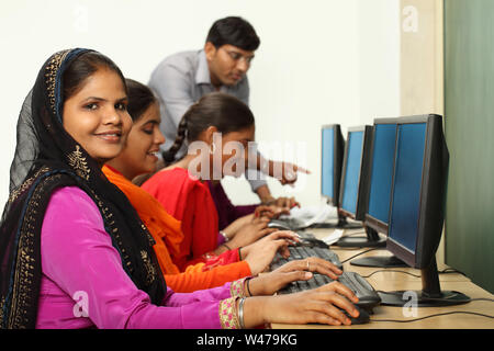 Women using computers with teacher assistance Stock Photo