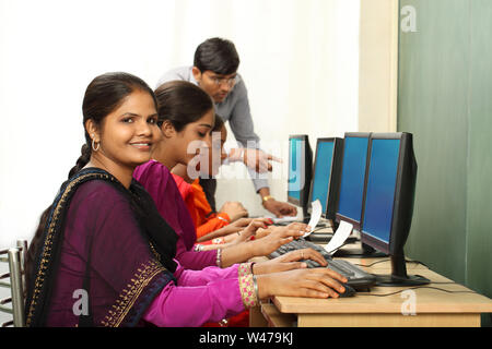 Women using computers with teacher assistance Stock Photo