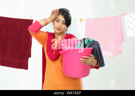Indian woman drying clothes and wiping her forehead Stock Photo