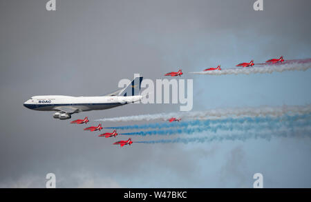 RAF Fairford, Glos, UK. 20th July 2019. Day 2 of The Royal International Air Tattoo (RIAT) with military aircraft from around the world assembling for the world’s greatest airshow which runs till 21 July. Image: A highlight of day 2 is the flypast by the RAF Red Arrows aerobatic display team in formation with a BOAC speedbird liveried Boeing 747. Credit: Malcolm Park/Alamy Live News. Stock Photo