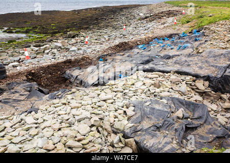 An archaeological dig at the Knowe of Swandro on Rousay, Orkney, Scotland, UK showing plastic sheeting and rocks used to protect the site over winter Stock Photo