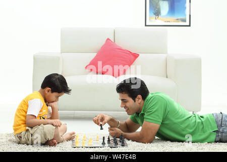 Man with his son playing chess at home Stock Photo