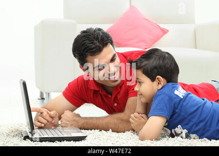 Man assisting his son in using laptop Stock Photo