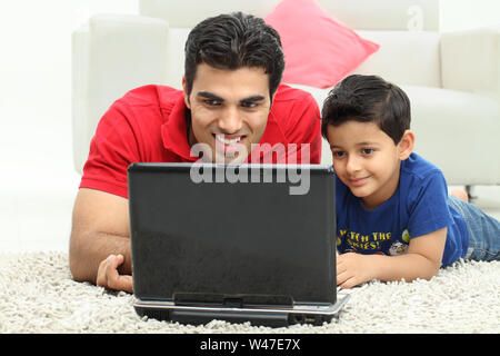 Man assisting his son in using laptop Stock Photo