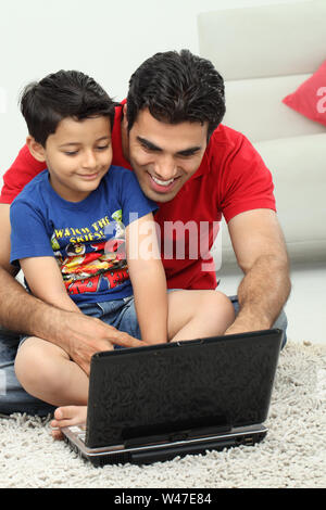 Man assisting his son in using a laptop Stock Photo