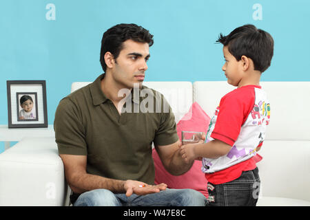 Boy giving water to his father for taking medicines Stock Photo