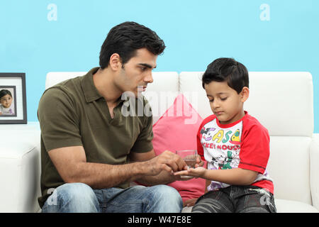 Man giving medicines to his son Stock Photo