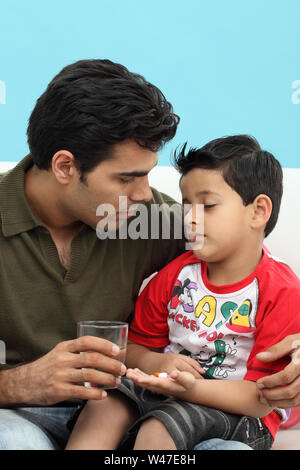 Man giving medicines to his son Stock Photo