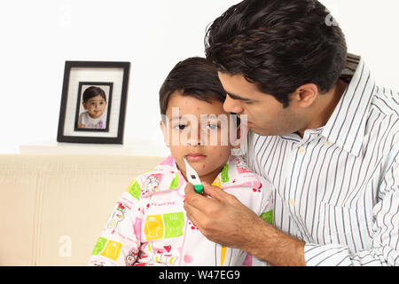 Man checking his son temperature suffering from chickenpox Stock Photo