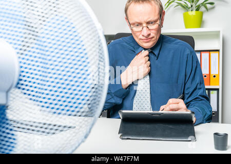 A businessman is working in heat in the office and sweating Stock Photo