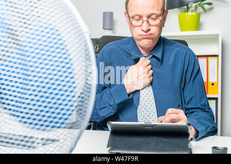 A businessman is working in a office and is sweating Stock Photo