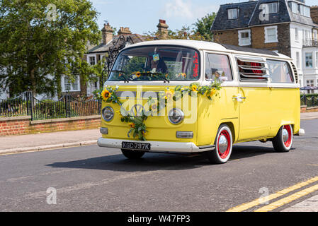Yellow VW Camper van Volkswagen Bus of Wolfsburg Bus Crew little yellow bus with hippy style flowers draped over front. Vehicle hire business Stock Photo