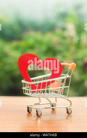 Red wooden heart in the trading cart. concept of buying love. nature background. Health care and purchase of medicines. Health care budget. Love for s Stock Photo