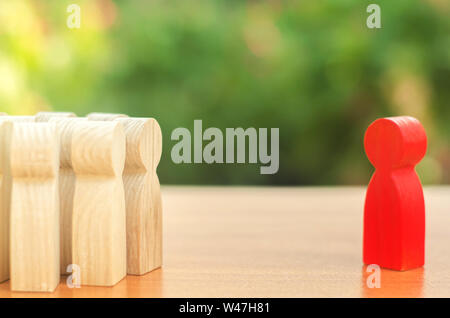 red figurine of a man stands aside from the crowd of people. Asociality, sociopathy. Rejected from society, lonely. Development of leadership and soci Stock Photo