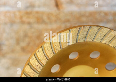 Part of the diamond grinding wheel against an orange-golden sandstone background close-up. Stock Photo