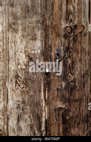 Old wooden gates with small metal lock. Old aged wood background Stock Photo