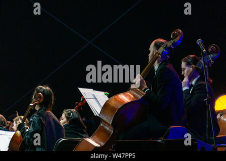 Russia, Moscow, April 30, 2019: cello player in orchestra with performers on background night time with light show, VDNH Stock Photo
