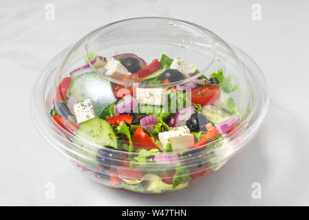 Fresh greek salad in a plastic package to take away for lunch on white marble background. close up Stock Photo