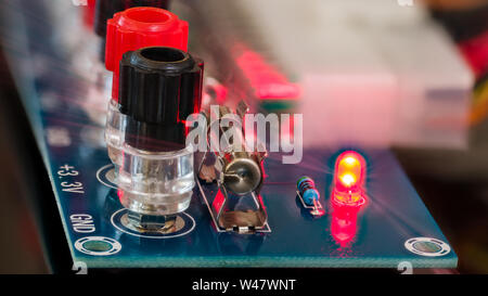 Power supply unit diagnostics. Electronic components detail on blue circuit board. Screw terminals, miniature fuse, red LED diode, resistor. Light ray. Stock Photo