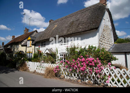 A typical whitewashed and thatched English country cottage stocked with traditional English flowers in Avebury, Wiltshire. Stock Photo