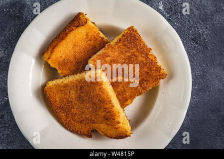 Yellow Corn Bread Squares Slices on Dark Rustic Background Stock Photo