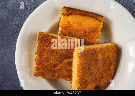 Corn Bread Squares Slices in White Plate on Dark Blue Rustic Background Stock Photo