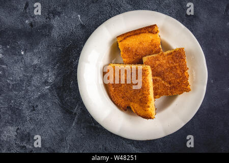 Corn Bread Squares Slices in White Plate on Dark Blue Rustic Background Stock Photo