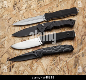 Penknives and hunting knives on a wooden background. Several knives on the table. Stock Photo