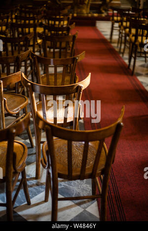 Row of wooden chairs in small chapel in Sicily with light falling on one chair Stock Photo