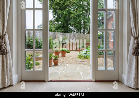 View of garden from inside house with french doors leading to a courtyard kitchen garden Stock Photo