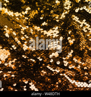 Golden iridescent sequins on fabric. Festive duotone background. Stock Photo