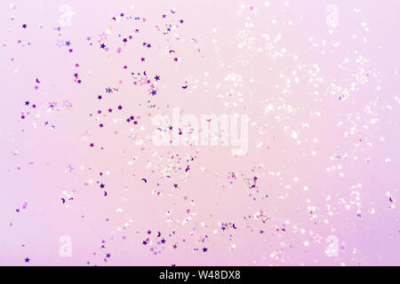 Holographic glitter confetti in pastel neon lights. Festive trendy background. Stock Photo