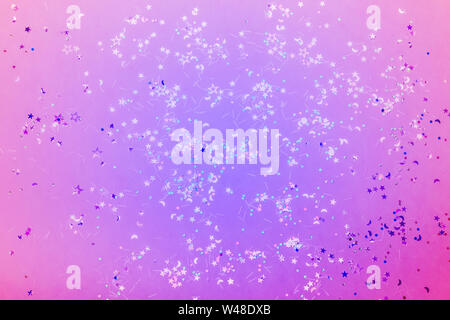 Holographic sparkles in neon lights. Festive trendy background. Stock Photo