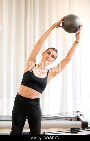Woman doing oblique workout while doing standing yoga pose with ball Stock Photo