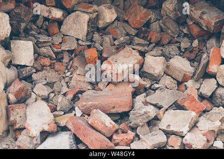 Pile of broken bricks, background. Texture, pattern, brick wall collapse. Destruction surface of building's facade. Debris. Stock Photo