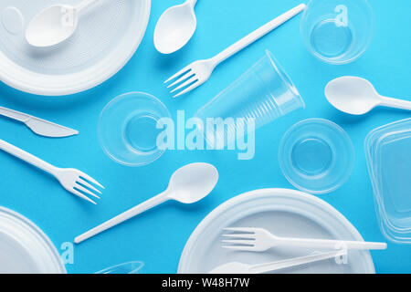 Various white plastic disposable tableware on blue background. Creative flat lay. Stock Photo