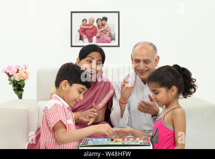 Boy and girl playing Ludo with their grandparents