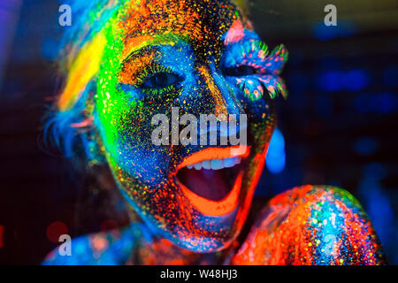 Concept. The girl smiles. Portrait of a girl painted in fluorescent powder Stock Photo