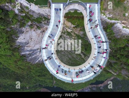 (190721) -- BEIJING, July 21, 2019 (Xinhua) -- Tourists go sightseeing on a transparent horseshoe-shaped cantilever bridge at the Yunyang Longgang Geological Park, one 'natural oxygen bar,' in Chongqing, southwest China, April 14, 2018. As more and more Chinese people are choosing to visit places that have fresh air, thick forests and are rich in negative ions, ecotourism becomes a fresh favoured choice across the country.    According to a report by the China Meteorological Service Association, trips to the regions granted as 'natural oxygen bars' by the association surged over 200 percent ye Stock Photo