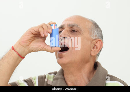 Old man using asthma inhaler Stock Photo