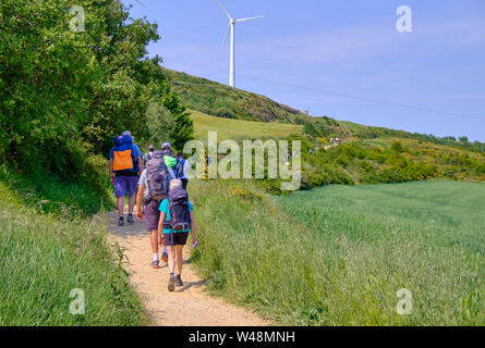 Long line of Pilgrims walking up to Alto del Pardon on the Camino de Santiago. Spain June 2019 viewed from the back Stock Photo