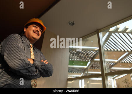 Low angle view of an Indian architect smiling with his arms crossed Stock Photo