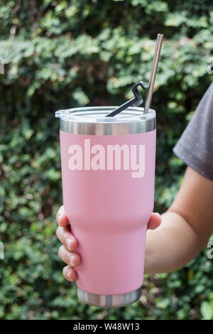 Hand on thermos tumbler mug with metal drinking straw, stock photo Stock Photo